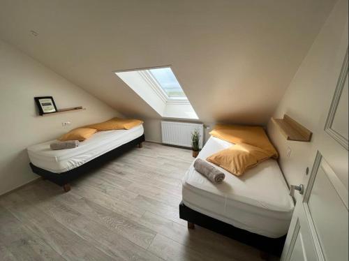two beds in a attic bedroom with a window at Slow Travel Mývatn - Þúfa - Private Homestay in Myvatn
