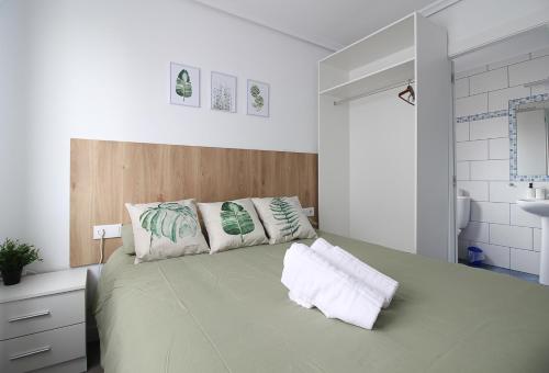 Un dormitorio con una gran cama verde con almohadas en loft con office santander, en Santander
