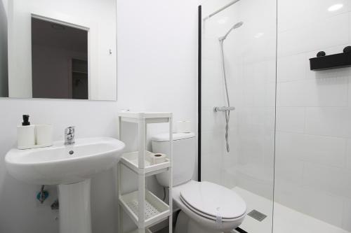 Baño blanco con aseo y lavamanos en La maruca loft, en Santander