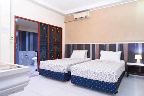 a bedroom with two beds and a bathroom at Guesthouse Phuket Airport in Ban Bo Han
