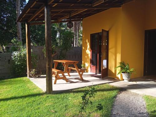 a wooden picnic table in a yard with a house at Casa Recanto das Mangueiras Japaratinga - Alagoas in Japaratinga