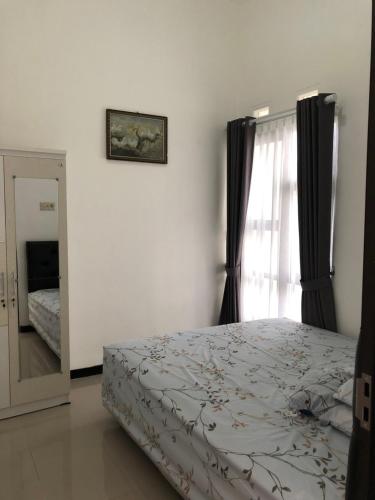 Schlafzimmer mit einem Bett, einem Fenster und einem Spiegel in der Unterkunft Homestay Syariah Orchard Family D30 in Sengkaling