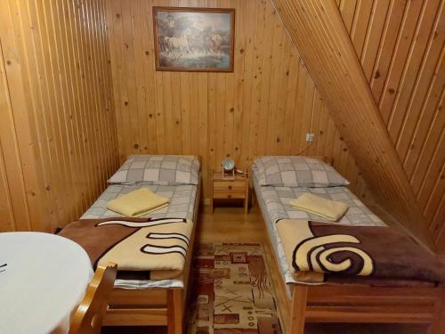 two twin beds in a room with wooden walls at u Marii Gał in Leśnica