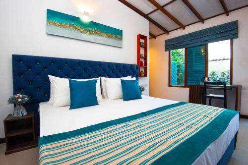 1 dormitorio con 1 cama grande y cabecero azul en Ocean Gateway Dickwella, en Dikwella