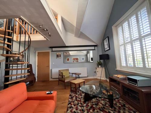 uma sala de estar com um sofá laranja e uma mesa em Retro penthouse flat, close to parks and centre em Liverpool