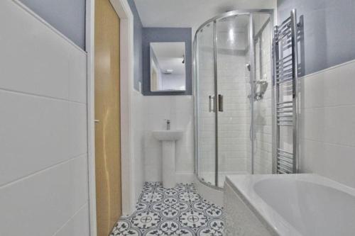 a bathroom with a shower and a tub and a sink at Retro penthouse flat, close to parks and centre in Liverpool