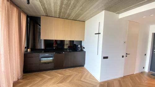 a kitchen with white cabinets and a wooden floor at J. Ralio apartamentai in Vilnius