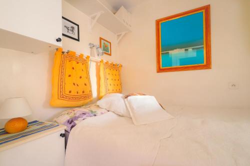 ein weißes Zimmer mit einem Bett und einem Fenster in der Unterkunft Le lutin in Saint-Laurent-du-Var