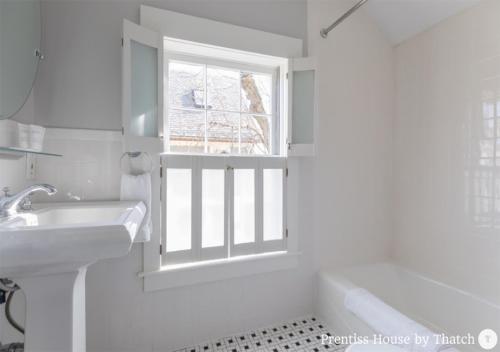 baño blanco con lavabo y ventana en Prentiss House by Thatch en Cambridge