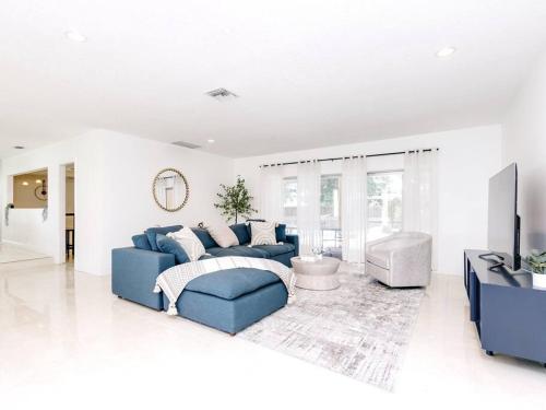 a living room with a blue couch and a tv at Modern Spacious 5-Bedroom Home with Pool in Hollywood