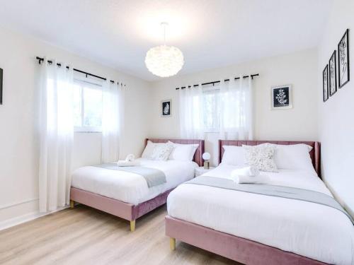 two beds in a bedroom with white walls and windows at Modern Spacious 5-Bedroom Home with Pool in Hollywood
