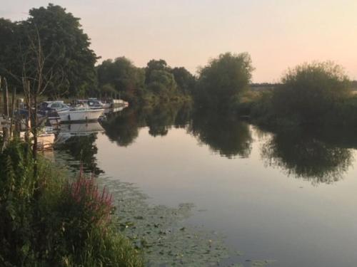a river with boats and trees in the water at Bens Hollow with hot tub in Bredon