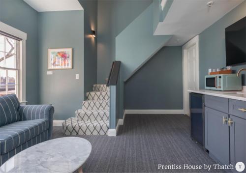 a living room with a couch and a stair case at Prentiss House by Thatch in Cambridge