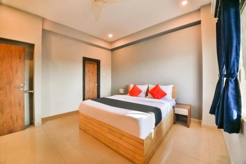 a bedroom with a large bed with red pillows at Capital O Amit Palace in Bhilwara