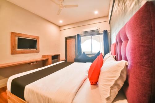 a hotel room with a bed and a tv at Capital O Amit Palace in Bhilwara