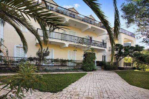 a large white building with palm trees in front of it at Dolphin Apartment 4 in Keri