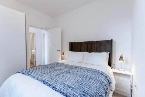 a white bedroom with a large bed with a blue blanket at Flat at Elgin Av Maida Vale W9 in London