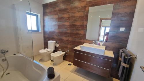 a bathroom with a tub and a toilet and a sink at Quinta do Pinheiro Premium by Sunny Deluxe in Olhos de Água
