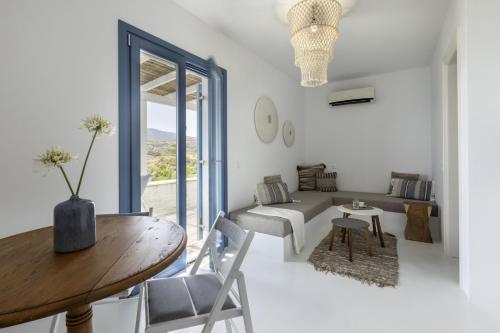 a white living room with a wooden table and chairs at The White House by the beach in Andros