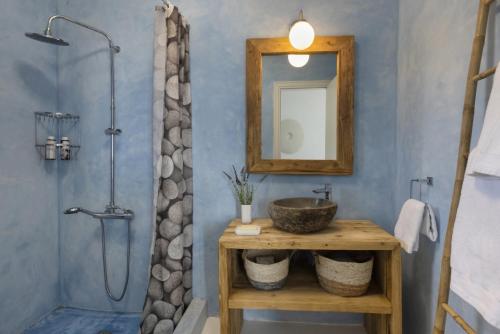 a bathroom with a sink and a mirror and a shower at The White House by the beach in Andros