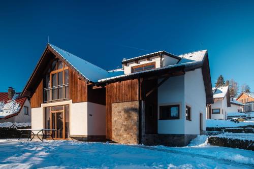 a house with snow on the ground in front of it at Residence Lipno in Lipno nad Vltavou