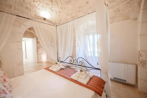 ein Schlafzimmer mit einem großen weißen Bett mit einem Fenster in der Unterkunft New Trulli Eden 101 with private pool and jacuzzi in San Michele Salentino