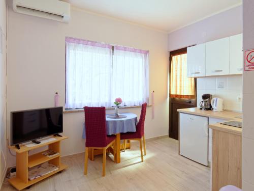 eine Küche mit einem Tisch und Stühlen sowie einem TV in der Unterkunft Apartments Marta in Novigrad Istria
