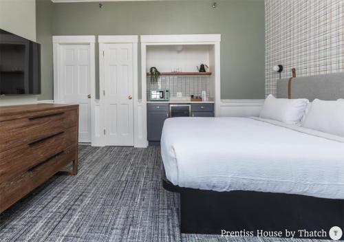 a bedroom with a large white bed and a kitchen at Prentiss House by Thatch in Cambridge