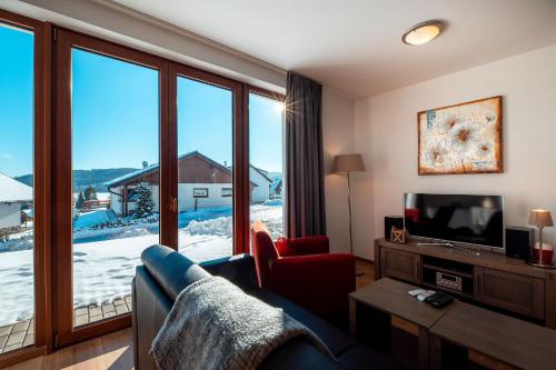 a living room with a couch and a large window at Residence Lipno in Lipno nad Vltavou