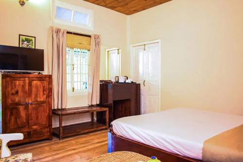 a bedroom with a bed and a television and a window at Bougainvillea Retreat & Spa in Kāhārpāra