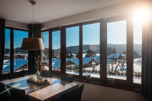 a dining room with a table and a large window at Residence Lipno in Lipno nad Vltavou