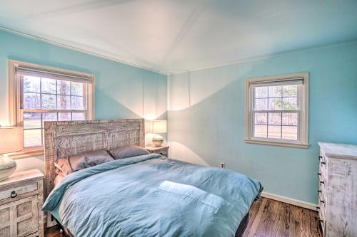 1 Schlafzimmer mit einem Bett mit blauen Wänden und 2 Fenstern in der Unterkunft Lovely Freehold Home with Deck, 16 Mi to Slopes in Freehold