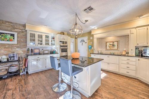 a kitchen with white cabinets and a island with chairs at Stunning Rogers Villa with Pond about 7 Mi to Lake in Rogers