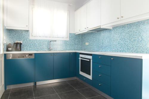 a blue kitchen with white cabinets and blue tiles at Vassiliki Residence Skyros Island in Skiros