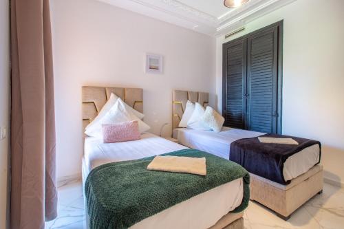 twee bedden in een kamer met witte muren bij Luxe et Cosy - 3 Chambres - Fitness - Wifi in Marrakesh