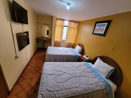 Habitación de hotel con 2 camas y TV de pantalla plana. en Hostal Cristal de luna, en Arequipa