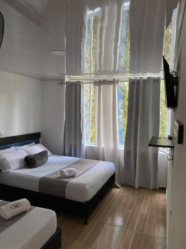 a bedroom with two beds and a window at Hotel Pass, Laureles Medellín in Medellín