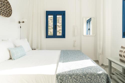 a white bedroom with a bed with a blue window at Alasthas in Gavrion