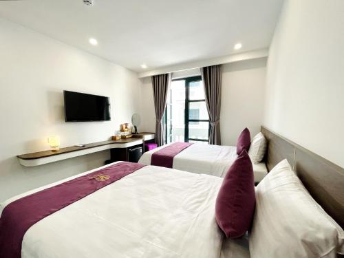 a hotel room with two beds and a television at Myrtle Boutique Hotel Phu Quoc in Phu Quoc