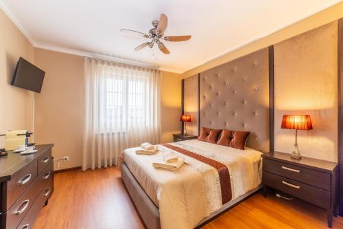 a bedroom with a large bed and a ceiling fan at Boa Vida Alojamentos in Vagos