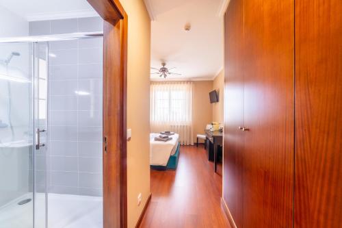 a bathroom with a shower and a bedroom at Boa Vida Alojamentos in Vagos