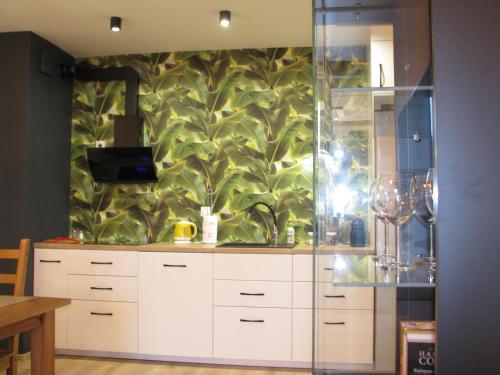 uma cozinha com armários brancos e uma parede verde em 4You Apartament em Bialystok