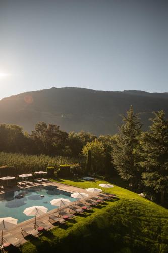 an aerial view of a pool with umbrellas and chairs at Design Hotel Tyrol in Rablà