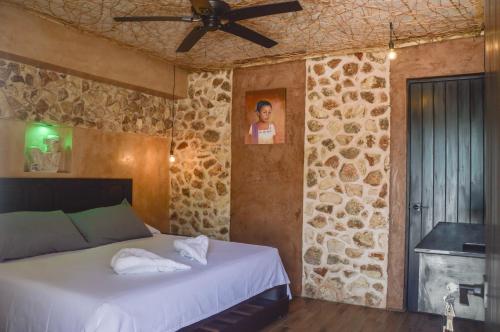a bedroom with a bed and a stone wall at Habitaciones Colonial Zaci in Valladolid