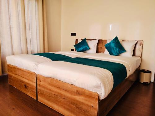 a bedroom with a large wooden bed with blue pillows at Thiksey Eco Homestay in Ranbirpura