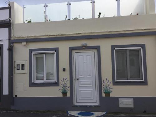 una casa con una porta bianca e due finestre di Casa Amarela AL 3030 a Horta