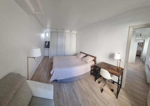 a bedroom with a bed and a table and a couch at Appartement luxueux dans maison bourgeoise parisienne in Levallois-Perret