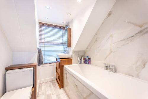 ein Badezimmer mit einer großen weißen Badewanne und einem Waschbecken in der Unterkunft Stylish, modern, Kensington apartment in London
