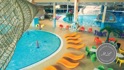a large swimming pool in a mall with orange chairs and a swimming pool at Parkside 41 - Located on Butlins Skegness Caravan Village, WiFi - Meadow Lakes Caravan & Lodge Hire in Lincolnshire