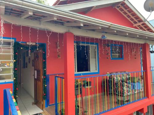 ein rotes Haus mit einem Balkon mit Weihnachtsdekoration in der Unterkunft Pousada Arco Iris in Gonçalves